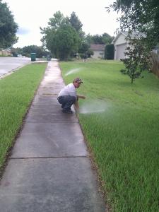 an Elk Grove Sprinkler Repair tech adjusts a pop up head